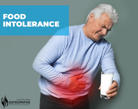 Man clutching stomach in pain while holding a glass of milk showing symptoms of food intolerance