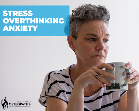 Thoughtful woman with short hair holding a mug, looking pensive and affected by stress or anxiety.
