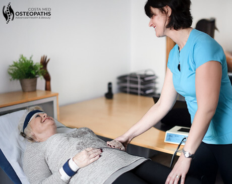 Sonja van Kommer providing a gentle SCIO treatment to a smiling patient at Costa Med Osteopaths