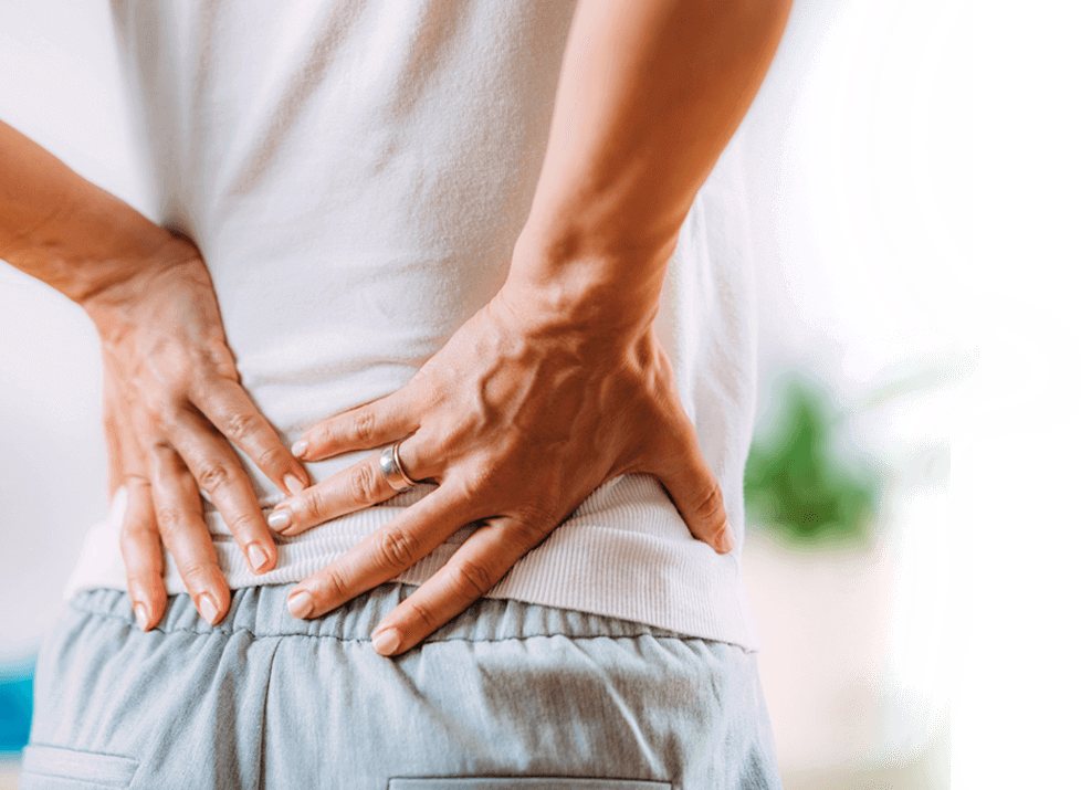 Person holding lower back in pain, showing location of discomfort