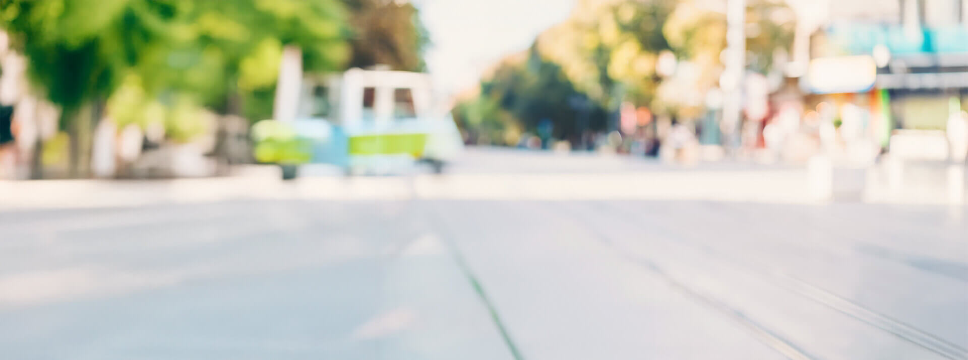 Blurry city street scene with trees and tram in the background, suggesting motion and energy
